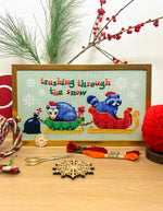 Trashing Through The Snow cross stitch pattern by NeedleLot Designs, raccoons in a sleigh in the snow