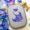 Front view of Rays of the Deep stingray and manta ray pattern. There are two rays, one big manta ray and a small stingray behind. They both contain mainly blue and purple colors and have sparkles on their backs. They are surrounded by white bubbles.