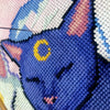 Extreme closeup of right-hand side of Smitten Kittens cross stitch pattern, and picture of the work in progress. Needle is sticking upwards. Danish method of stitching is being used. Moon on cats head is a vibrant yellow. Cat is cornflower blue.