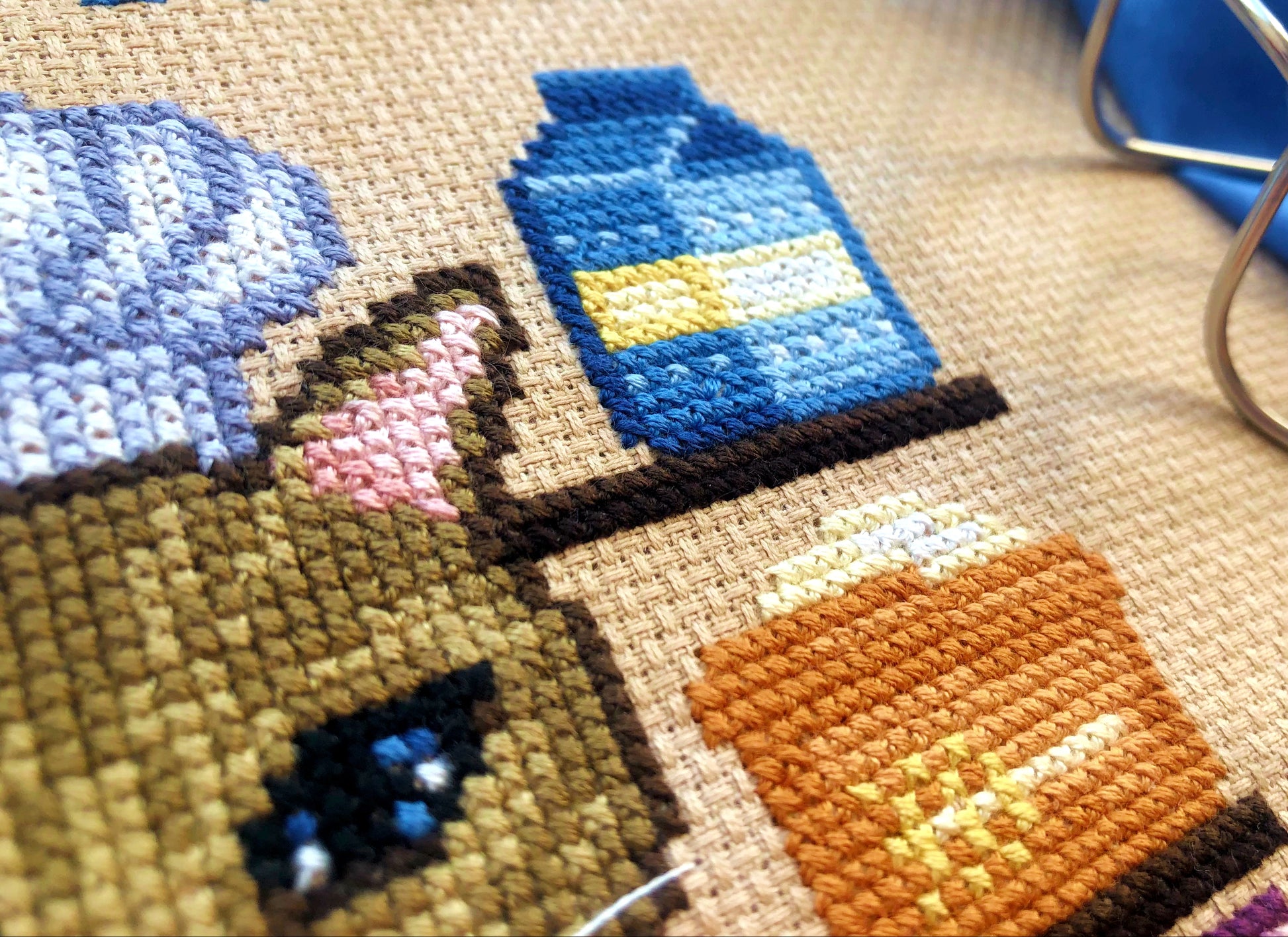 Closeup of milk carton and wheat. Stitches are fluffy and tidy. Colors are brown, orange, pink and yellow. Products are placed on shelves.