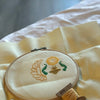 Picture of the work-in-progress of the Egyptian scarab cross stitch pattern. A small part of the pattern has been stitched: only the head, front paws, sun and part of the lefthand wing are visible. Piece is framed in a hoop, bobbin in the foreground.