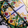 Extreme closeup of bottom half of the scene, with lots of vegetation. There are several plants and flower bulbs here, in lots of different colors. Flower bulbs are red with garnet outlines. There are leaves, these are gold, green, teal and black.